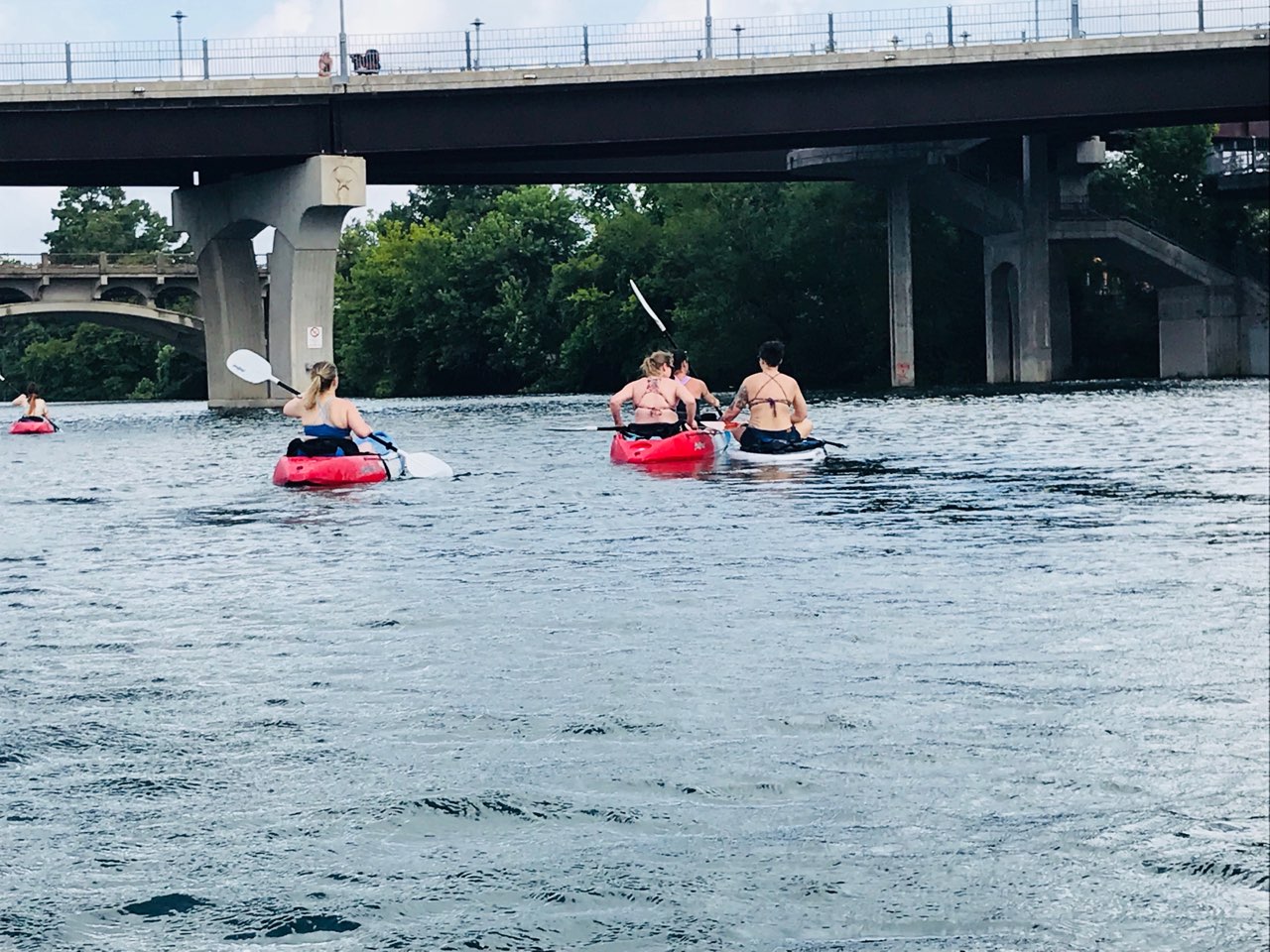 Clients kayaking on town lake heading under the congress bridge